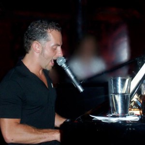 Mark Weiser singing into the microphone at a Dueling Pianos NYC show.
