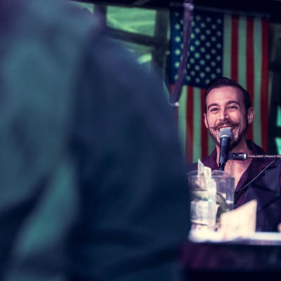 Piano man smiles with flag in the background