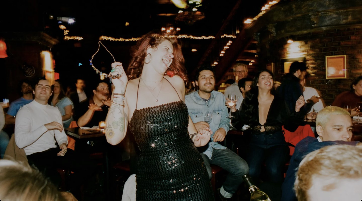 A red-haired bachelorette dances and sings along in front of a happy crowd.