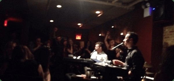 Two dueling pianists playing modern dueling pianos songs at a piano bar show.