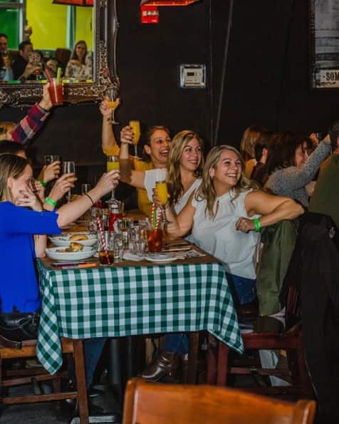 A table of women toasting with bottomless mimosas at Boozy Brunch.