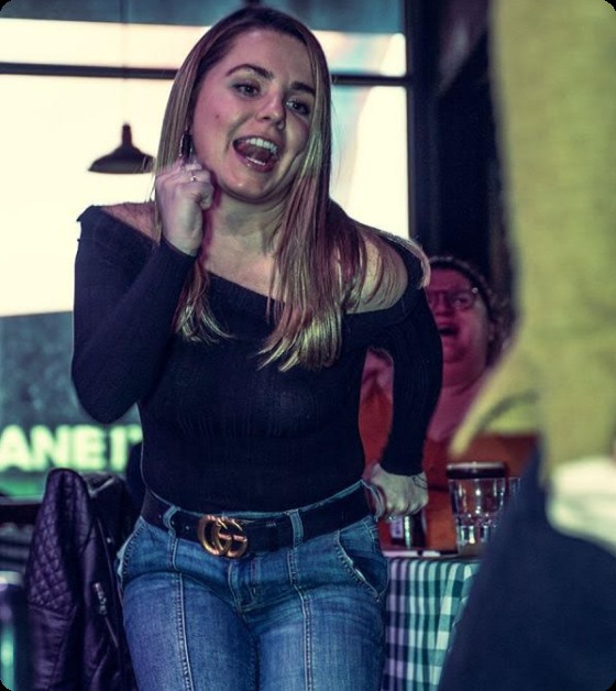 A young woman jumps out of her seat to dance at a Boozy Brunch show.