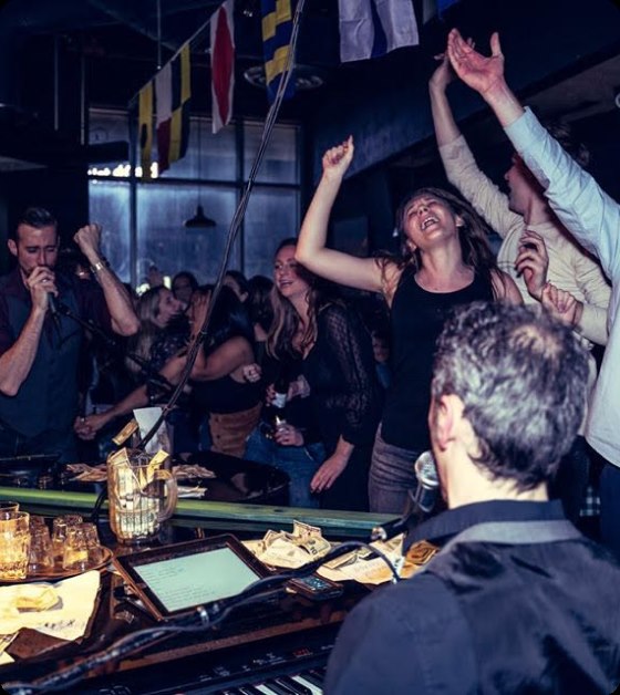 The whole crowd on their feet and dancing at Dueling Pianos.