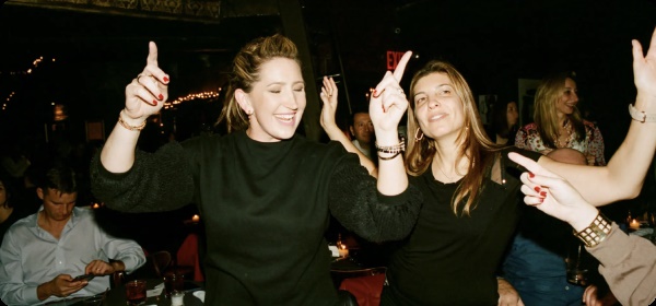 Two women point their fingers while dancing to the music.