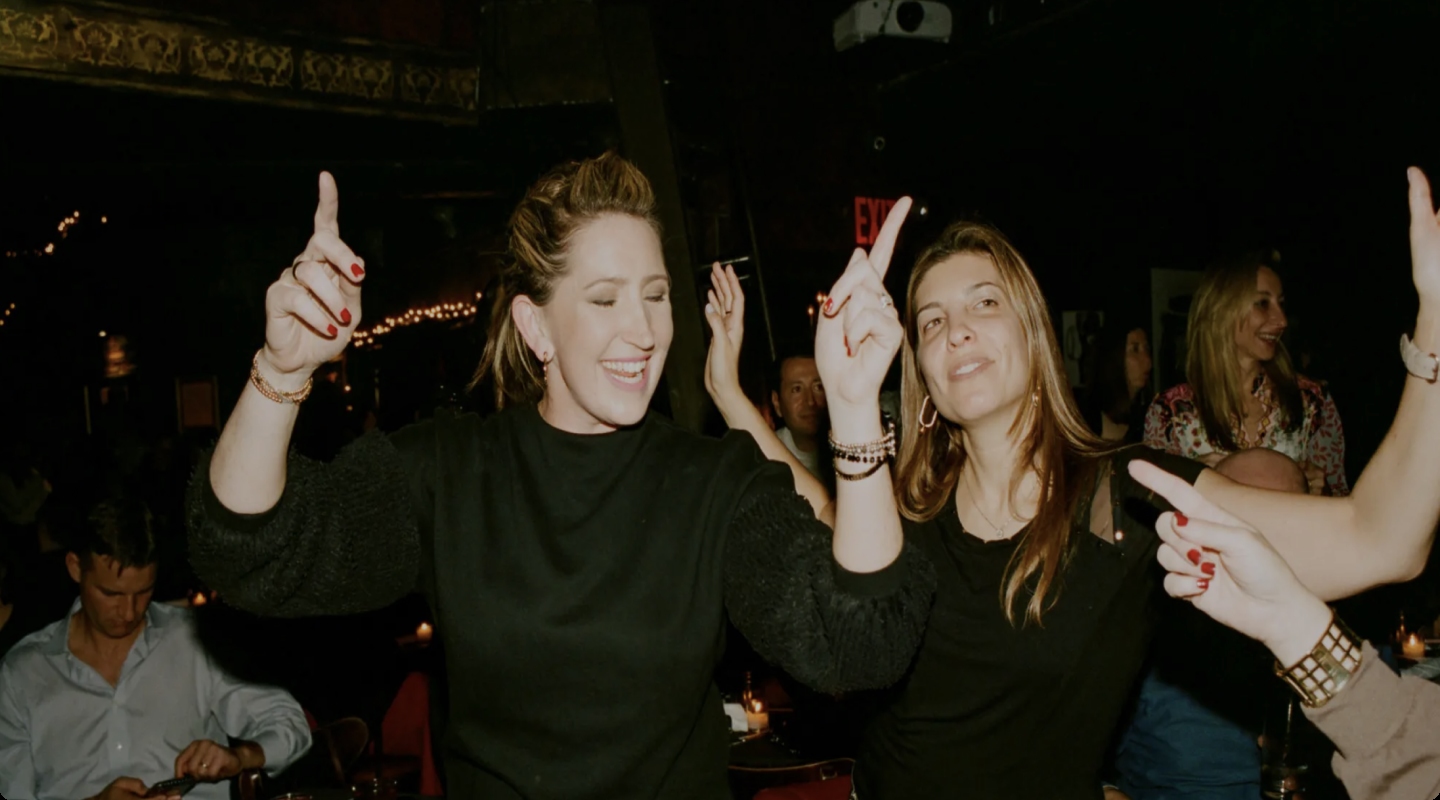 Two women point their fingers while dancing to the music.