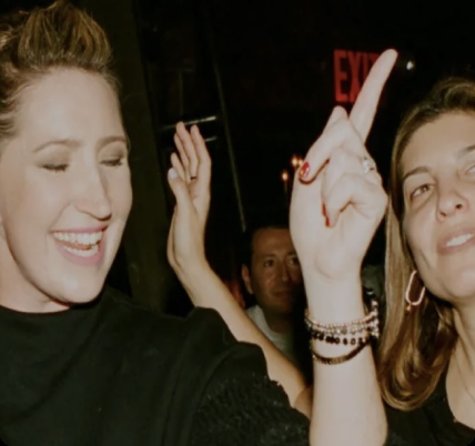 Two women point their fingers while dancing to the music.