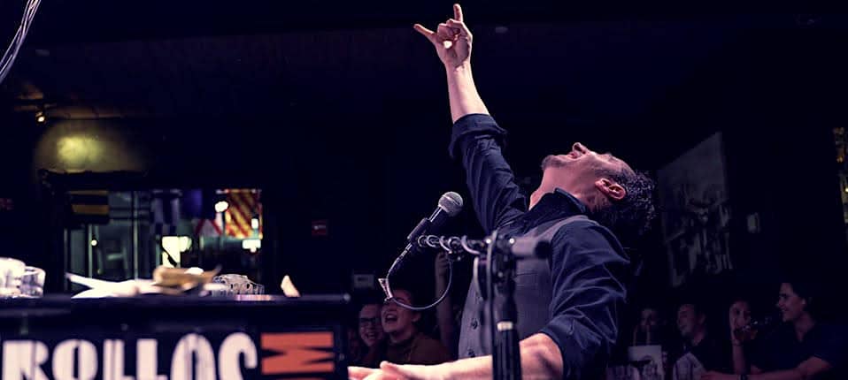 The piano player points his fingers to the sky at a Dueling Pianos show.