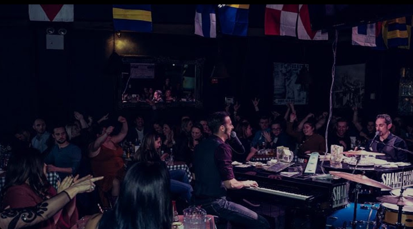 Two dueling piano players bantering in the center of the crowd.