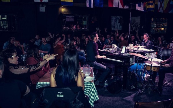 Two dueling piano players bantering in the middle of the crowd.